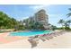 Inviting outdoor swimming pool with lounge chairs, complemented by lush palm trees and clear blue skies at 3040 Grand Bay Blvd # 234, Longboat Key, FL 34228