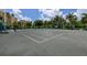 Spacious tennis court surrounded by lush greenery, set against residential buildings, under a clear sky at 3040 Grand Bay Blvd # 234, Longboat Key, FL 34228