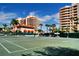 Well-maintained tennis court set against a backdrop of palm trees and residential buildings under a sunny sky at 3040 Grand Bay Blvd # 234, Longboat Key, FL 34228