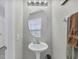 Brightly lit powder room with a white pedestal sink, an oval mirror, and bronze faucets underneath modern lighting at 3826 Virga Blvd, Sarasota, FL 34233
