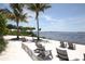 Relaxing beach with lounge chairs, palm trees, and a serene waterfront view at 396 Aruba Cir # 302, Bradenton, FL 34209