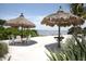 Inviting beach with charming thatched umbrellas and comfortable seating on the white sand at 396 Aruba Cir # 302, Bradenton, FL 34209