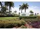 The Beach Club sign nestled in manicured landscaping featuring flowering plants and lush bushes at 396 Aruba Cir # 302, Bradenton, FL 34209