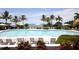 A large pool surrounded by seating with umbrellas and palm trees with a view of the water at 396 Aruba Cir # 302, Bradenton, FL 34209