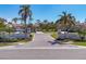 Community entrance with twin guardhouses adorned with white walls, manicured lawns, palm trees, and the name 'Villa Palmeras' at 4416 Calle Serena, Sarasota, FL 34238