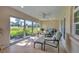 A bright, airy sunroom with neutral decor offers beautiful outdoor views through large windows at 4416 Calle Serena, Sarasota, FL 34238