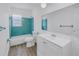Bright bathroom featuring turquoise tile, a white vanity, and neutral wood-look flooring at 4461 Maceachen Blvd, Sarasota, FL 34233