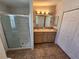 Bathroom featuring dual sinks, tile flooring, a glass door shower, and a linen closet at 4923 5Th Street W Ct, Bradenton, FL 34207
