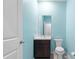 Powder room featuring blue walls, toilet, vanity with marble countertop, and a decorative mirror at 559 Spotted Slipper Pl, Ruskin, FL 33570
