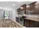 Kitchen featuring granite countertops, dark cabinets, stainless steel appliances, and decorative backsplash at 559 Spotted Slipper Pl, Ruskin, FL 33570