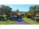 A grand entrance of the clubhouse featuring a covered drop-off area and lush landscaping at 5621 Palm Aire Dr, Sarasota, FL 34243