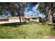 Beautifully landscaped home with mature trees, a well-maintained lawn, and a spacious driveway at 5621 Palm Aire Dr, Sarasota, FL 34243