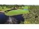 An elevated view of the golf course featuring a green, water, sand trap, and fountain at 5621 Palm Aire Dr, Sarasota, FL 34243