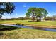Scenic golf course view features lush green grass, mature trees, and a peaceful stream at 5621 Palm Aire Dr, Sarasota, FL 34243