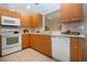 Well-lit kitchen with wooden cabinets, white appliances, and a view to the dining area at 5621 Palm Aire Dr, Sarasota, FL 34243