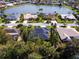 Overhead shot of home surrounded by lush trees near a serene lake, highlighting the tranquil neighborhood setting at 5646 Country Lakes Dr, Sarasota, FL 34243