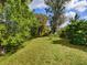 A large, manicured lawn with mature trees and landscaping provides a serene and private outdoor space at 5646 Country Lakes Dr, Sarasota, FL 34243