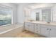 Bright bathroom features a soaking tub, double vanity with white cabinets and large mirror at 5646 Country Lakes Dr, Sarasota, FL 34243