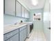Efficient laundry room featuring front-load washer and dryer, built-in cabinets, and utility sink at 5646 Country Lakes Dr, Sarasota, FL 34243