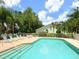 A sparkling pool with lounge chairs and a table is surrounded by lush landscaping and privacy fencing at 5646 Country Lakes Dr, Sarasota, FL 34243