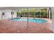 Private backyard pool with brick-paved deck, screened enclosure, and lush tropical landscaping at 5646 Country Lakes Dr, Sarasota, FL 34243
