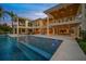 Stunning rear exterior of a two-story home with a large pool, covered patio, and lush landscaping at sunset at 612 Juan Anasco Dr, Longboat Key, FL 34228