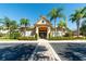 Charming clubhouse entrance with palm trees, lush landscaping, and elegant architectural details at 6512 Moorings Point Cir # 201, Lakewood Ranch, FL 34202