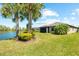 Backyard with a serene pond view and well-maintained lawn, complemented by mature palm trees, offering a peaceful retreat at 6912 Gosport Cv, Bradenton, FL 34202