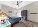 Cozy bedroom with wood-look floors, ceiling fan, a blue comforter, and a navy wardrobe at 6912 Gosport Cv, Bradenton, FL 34202
