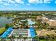 Aerial view of a resort-style pool and amenity center with a lakefront pier and bocce ball courts at 6912 Gosport Cv, Bradenton, FL 34202