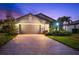 Charming single-Gathering home displaying a two-car garage, brick driveway, and landscaped front yard at twilight at 6912 Gosport Cv, Bradenton, FL 34202