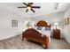 Main bedroom with wood floors, tray ceiling, a ceiling fan, and an en-suite bathroom entrance at 6912 Gosport Cv, Bradenton, FL 34202
