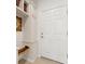 Mudroom entryway with a built-in bench, storage cabinets, shelving, and a white exterior door at 6912 Gosport Cv, Bradenton, FL 34202