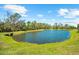 Picturesque view of a calm pond lined with vibrant green grass and mature trees under a clear blue sky at 6912 Gosport Cv, Bradenton, FL 34202