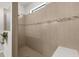 Walk-in shower featuring sleek neutral tiling and a convenient shower seat with a decorative horizontal stripe at 6912 Gosport Cv, Bradenton, FL 34202