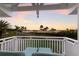 Scenic balcony view with lounge chairs overlooking lush greenery and the water at sunset at 766 Bayshore Dr, Terra Ceia, FL 34250
