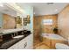 Bright bathroom features marble tile, soaking tub, frameless shower, and dark granite countertops at 766 Bayshore Dr, Terra Ceia, FL 34250