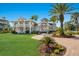 Stunning two-story home with a manicured lawn, brick pathway, and lush tropical landscaping at 766 Bayshore Dr, Terra Ceia, FL 34250