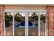 Inviting pool area with a view of palm trees and lounge chairs through sliding glass doors at 766 Bayshore Dr, Terra Ceia, FL 34250