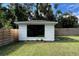 A modern white shed offers additional storage or workspace in a landscaped backyard with a wooden fence at 7735 Westmoreland Dr, Sarasota, FL 34243
