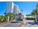 View of building exterior at gated entrance with palm trees and an American flag at 9393 Midnight Pass Rd # 506, Sarasota, FL 34242