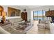 Bright living room with neutral colored furnishings and water views from a large window at 9393 Midnight Pass Rd # 506, Sarasota, FL 34242
