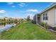 The backyard features a view of the pond, grassy lawn, and screened lanai on the home at 9847 Hawk Nest Ln, North Port, FL 34287