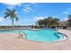 Large community pool area with ample lounge chairs and palm trees against a blue sky at 9847 Hawk Nest Ln, North Port, FL 34287