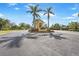 Community entrance with a decorative sign surrounded by palm trees and colorful landscaping at 9847 Hawk Nest Ln, North Port, FL 34287