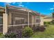 View of the home's screened lanai with rocking chairs and landscaping at 9847 Hawk Nest Ln, North Port, FL 34287