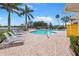 Community pool surrounded by tropical palm trees and comfortable lounge chairs at 9847 Hawk Nest Ln, North Port, FL 34287