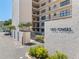 Exterior shot of Lido Towers building entrance, with palm trees and lush landscaping at 1001 Benjamin Franklin Dr # 510, Sarasota, FL 34236