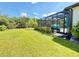 Expansive backyard featuring lush green lawn, mature trees, and screened lanai with private pool at 10179 Milky Way Cir, Sarasota, FL 34241