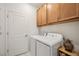 Bright laundry room features a white washer and dryer plus wooden cabinets and door at 10179 Milky Way Cir, Sarasota, FL 34241